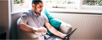Arden University student on laptop sitting by window